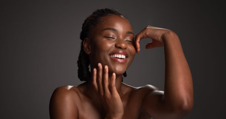 Skincare, happy and black woman in studio for natural beauty, wellness and collagen benefits. Space, dermatology and person with touch, smile and spa aesthetic for healthy skin on dark backgroundの写真素材