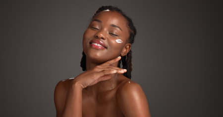 Space, face cream and black woman in studio for skincare, facial and natural beauty on dark background. Mockup, dermatology and person with lotion, moisturizer and cosmetics for glow, shine or healthの写真素材