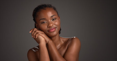 Skincare, happy and woman with glow, portrait and natural cosmetics for healthy skin or mockup space. Gray background, black person and self care with dermatology, confident and studio in Nigeriaの写真素材
