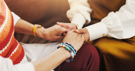 Holding hands, support and women friends on sofa with comfort, love and bonding together. Trust, compassion and female people with connection in living room for empathy, care or solidarity in home.の写真素材