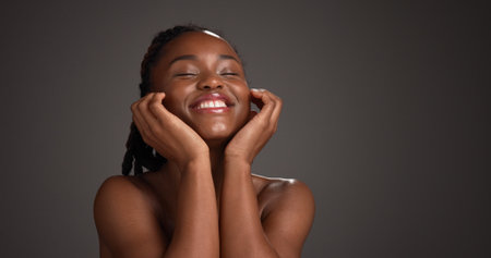 Black woman, skincare and happy for touch in studio, natural glow or mockup space on dark background. African girl, beauty and smile with thinking, cosmetics or soft texture with dermatology benefitsの写真素材