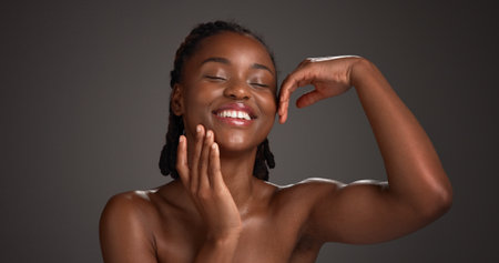 Skincare, happy and black woman with hands in studio for hydration, wellness and natural beauty. Space, dermatology and person with touch, smile and aesthetic for healthy skin on dark backgroundの写真素材