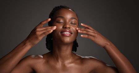 Skincare, natural beauty and black woman with hands in studio for hydration, wellness and cosmetics. Space, dermatology and person with touch, smile and aesthetic for healthy skin on dark backgroundの写真素材