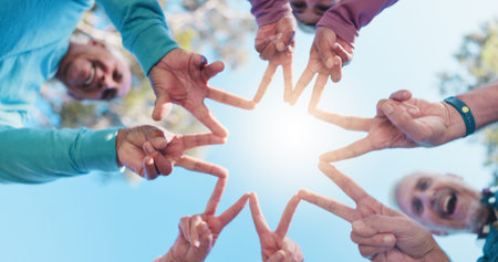 Senior people, hands and star for collaboration, solidarity or fitness support in outdoor park. Blue...