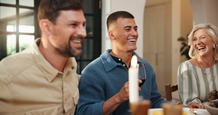 Laughing, family and thanksgiving dinner in home for holiday season, eating and funny conversation. Festive party, happy people and food at dining table for celebration event, bonding and traditionの写真素材