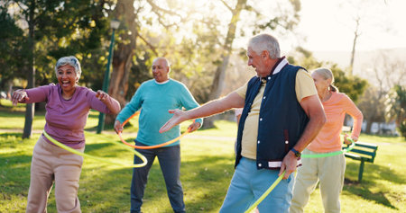 Senior people, park and workout with hoop for active retirement, wellness class or laugh. Elderly friends, ring and fitness outdoor, funny joke or exercise for balance with group for cardio healthの写真素材