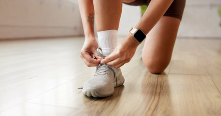 Person, hands and tying with shoes for workout preparation, exercise or indoor training. Closeup, active or legs with sneaker, tie or getting ready with laces for fitness, run or gym in health clubの写真素材