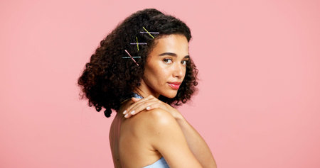 Portrait, skincare and woman in studio, beauty and dermatology with curly hair on pink background. Mockup space, gen z or person with shine, glow or cosmetics with hairstyle, healthy skin or wellnessの写真素材