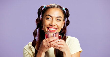 Makeup, lipgloss and portrait of woman in studio for choice, beauty treatment or glow. Happiness, cosmetology and gen z with person on purple background space for self care, cosmetics and shineの写真素材