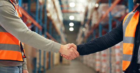 Supply chain, shaking hands and men in warehouse, agreement and logistics with partnership. Employees, bokeh and handshake in factory, distribution and onboarding with welcome, deal and introductionの写真素材