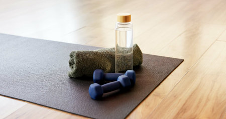 Mat, dumbbells and bottle with towel in yoga studio for fitness challenge, hydration or workout....
