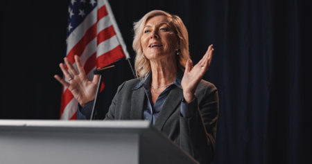 Politician, speech and woman with American flag on a stage for election, debate and voting campaign. Government, candidate and mature person for press conference, political policy and delegationの写真素材