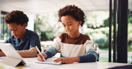 Tablet, homework and kids in house with education, learning or studying for test together. Writing, tech and boy children with knowledge for school assignment, assessment or exam by desk in apartmentの写真素材