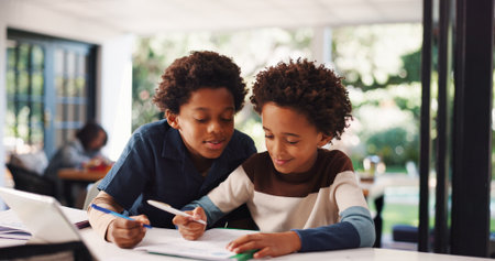 Book, homework and kids in house with education, learning or studying for test together. Writing, help and boy children with knowledge for school assignment, assessment or exam by desk in apartment.の写真素材