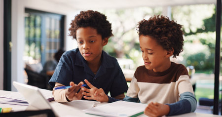 Book, homework and children in house with education, learning or studying for test together. Writing, help and boy kids with knowledge for school assignment, assessment or exam by desk in apartment.の写真素材