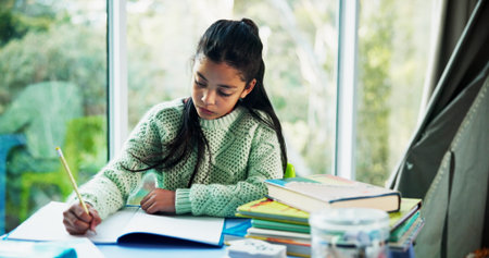 Student, learning and child writing in home for fine motor skills, language activity and assessment. Books, girl kid and handwriting practice in homeschool for academic development, literacy or studyの写真素材