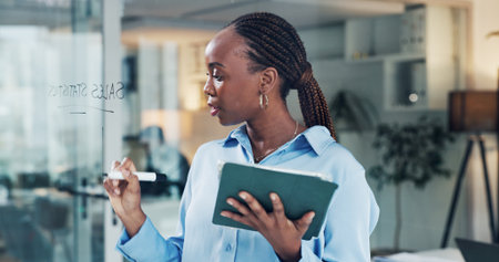Glass board, black woman or writing with tablet in office, review sales numbers or monitor selling goal. Employee target, track performance or manager with tech to share stats, set quota or strategyの写真素材