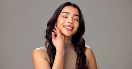 Beauty, skincare and woman in studio, happy and healthy skin with cosmetics, smile and mockup space. Soft, face and person with glow, gray background and self care for wellness with dermatologyの写真素材