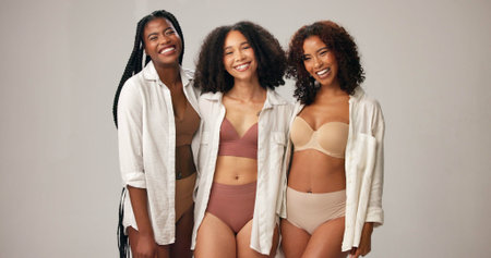 Portrait, underwear and women in studio for body positivity, wellness and funny with natural beauty. Diversity, lingerie and friends with confidence, inclusion and laugh on gray background spaceの写真素材