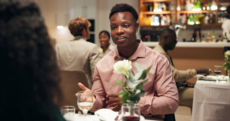 Couple, date and conversation in restaurant with wine for romance, anniversary celebration and love. Hospitality, talk and fine dining with man, woman and smile with diner discussion and bondingの写真素材