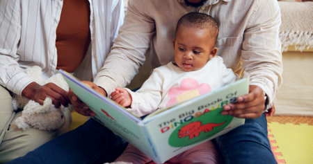 Family, child or reading with dinosaur book in home for story or childhood development. Mom, dad or toddler with kids novel, fairytale or literature for learning, bonding or fantasy together in houseの写真素材