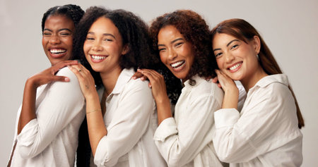 Portrait, happy and women for beauty in studio with cosmetics, natural shine and solidarity. People, diversity and laugh for makeup, healthy skin and self care support of makeover on white backgroundの写真素材