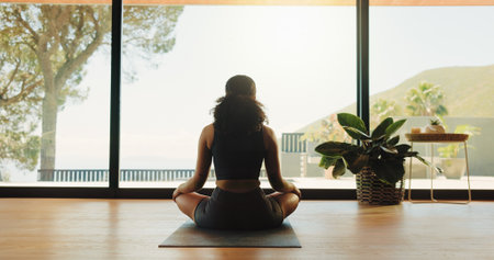 Woman, back view and meditation with zen for inner peace, yoga or spiritual wellness in studio. Calm, female person or yogi with chakra, mudra or mantra for balance or mindfulness in serene dojoの写真素材