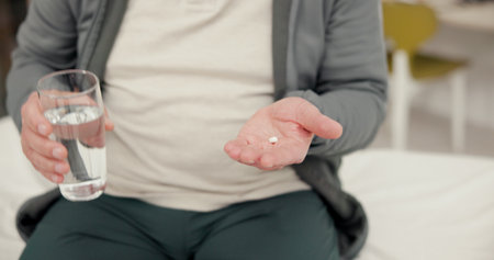 Pill, water and senior person hands in clinic for medical consultation with treatment for recovery. Healthcare, vitamins and elderly man with drugs, tablets or supplements with h2o for wellnessの写真素材