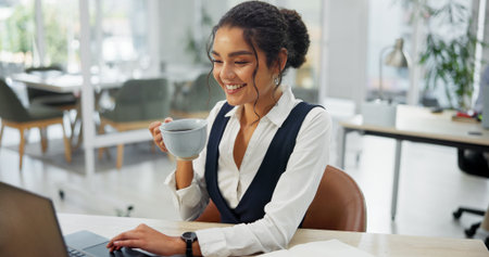 Woman, laptop and happy with coffee at office, scroll and review with project management at media company. Person, journalist or writer with smile, drink and computer for editing article at agencyの写真素材