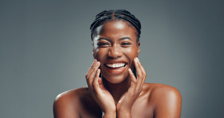Portrait, skincare and black woman in studio, funny and dermatology on gray background. Space, shine and African person with wellness, glow and beauty with cosmetics, healthy skin, humor and laughingの写真素材