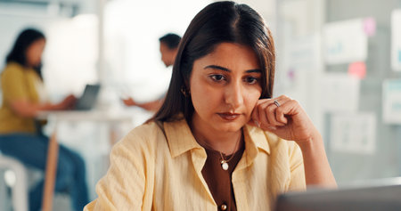 Woman, computer and review at startup in office, project management or decision at media company. Person, pc and serious with insight, perspective or problem solving with solution for job at agencyの写真素材