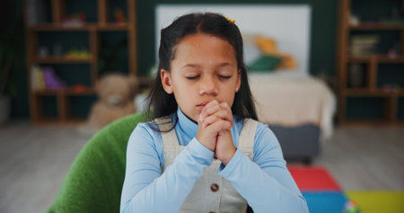 Girl, child and praying with hope in home for faith, trust or worship of god or belief. Development, kid or christianity with prayer hands or eyes closed for culture, religion or acceptance in houseの写真素材