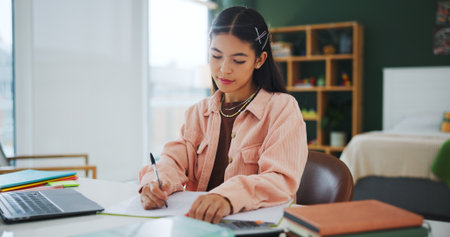 Education, university student and writing notes in home, learning knowledge or exam preparation. Studying, course revision and woman with laptop for academic assessment, quiz info or subject summaryの写真素材