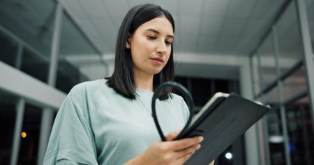 Doctor, tablet and woman in hospital with stethoscope, research and healthcare report at night. Technology, medical worker and person with cardiology update, telehealth or clinic results on overtimeの写真素材