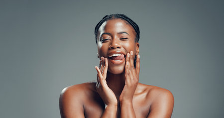 Portrait, skincare and black woman in studio, funny and dermatology on gray background. Space, tongue out and African person with beauty, glow and grooming with cosmetics, healthy skin and aestheticの写真素材