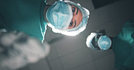 Low angle, doctor and people in hospital, portrait and surgical mask with medical service. Pov, procedure and employees in clinic, healthcare and emergency with face cover and treatment for injuryの写真素材