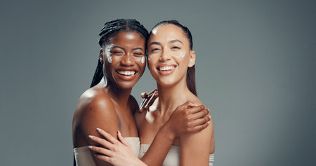 Beauty, cream and portrait of women in studio for skincare, glow and self care diversity. Shine, dermatology and aesthetic with people on gray background space for lotion, hydration and supportの写真素材