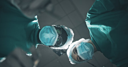 Below, doctor and people with portrait, surgery and surgical mask with emergency. Pov, group and employees in clinic, healthcare or medical service with face cover, procedure and treatment for injuryの写真素材