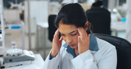Tired, scientist or woman in lab with headache from experiment fumes, chemical reaction or workload. Exhausted, person and migraine in workplace from medical research, science investigation or issue.の写真素材