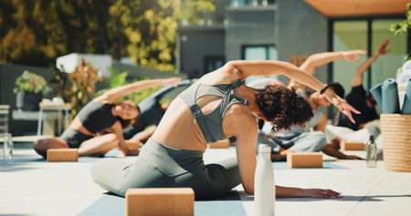 Woman, trainer and yoga class for fitness, stretching or back at wellness retreat. Yogi, group exercise and people with instructor at resort for balance, healing and health with side bend outdoorの写真素材