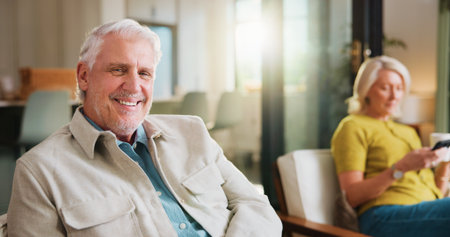 Break, portrait and smile of old man on sofa in living room of home with wife for retirement. Relax, weekend and wellness with happy senior people in apartment together for chilling or free timeの写真素材