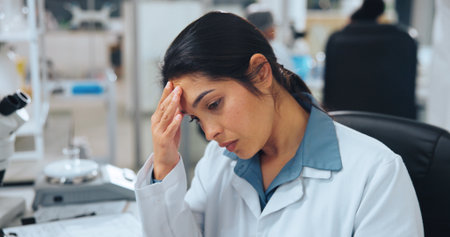 Tired, scientist or woman in lab with migraine from experiment fumes, chemical reaction or workload. Exhausted, person and headache in workplace from medical research, science investigation or issue.の写真素材