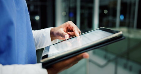 Nurse, tablet and hands in hospital for healthcare research, report or schedule in clinic at night. Technology, medical worker and person with online results, check email and bokeh on overtimeの写真素材