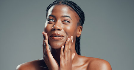 Beauty, thinking and black woman in studio for skincare, facial glow and soft texture for wellness. Mischievous expression, shine and person with smooth skin, self care and space on gray backgroundの写真素材