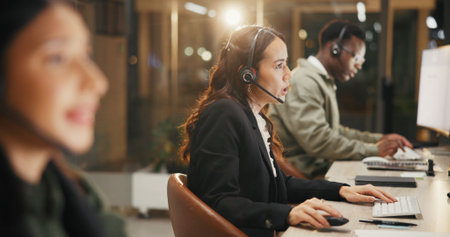 Woman, call center and consulting with headset at night for customer service or support at office. Female person, employee or agent talking for communication, helpdesk and overtime at workplaceの写真素材