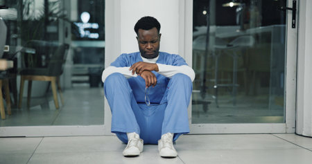 Tension, black man and nurse in hospital with crisis, mistake or pressure for treatment plan. Stress, burnout and African healthcare worker with fatigue for negative report for patient in clinic.の写真素材