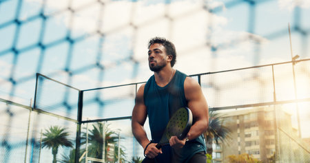 Fitness, outdoor and man with padel racket for game, summer training and ready for sport practice. Low angle, tennis court or athlete with gear for skills development, coordination exercise and matchの写真素材