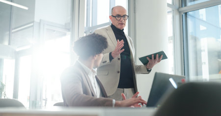 Feedback, manager and tablet with business person in office for conversation or development. App, collaboration and flare with corporate employee people at desk in workplace for project managementの写真素材