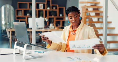 Black woman, reading and documents at house for accounting, finance report and statistics. Person, remote work and laptop with paperwork, revenue graphs and financial comparison for audit informationの写真素材