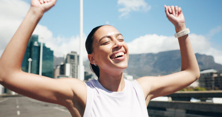 Happy woman, runner and winning with marathon success in city for fitness challenge or competition. Active, female person or winner with smile or fist pump for sport race, sprint or victory in townの写真素材